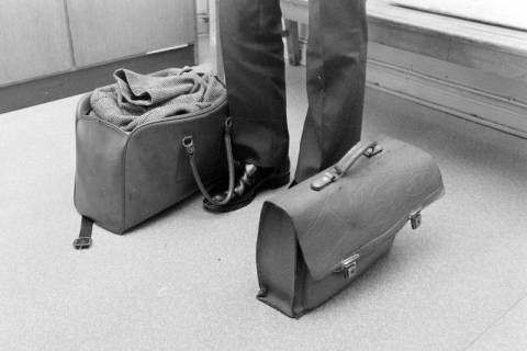 ARH NL Mellin 01-143/0014, Zwei Taschen rechts und links neben einem Menschen auf dem Boden stehend, ohne Datum