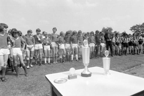ARH NL Mellin 01-144/0004, Vorne vier Pokale auf einem Tisch stehend und dahinter eine Reihe von jungen Fußballspielern, ohne Datum