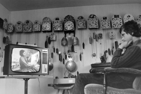 ARH NL Mellin 01-146/0017, Mehrere Pendeluhren an einer Wand und ein Junge vor einem Fernseher, ohne Datum