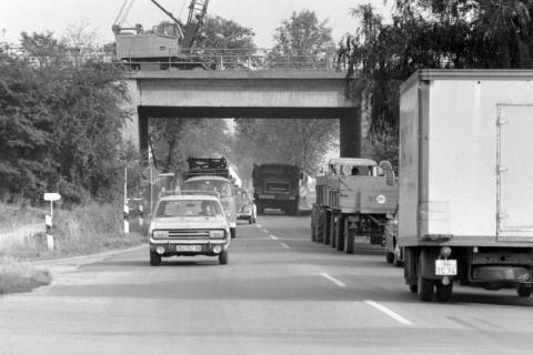 ARH NL Mellin 01-149/0007, Straßenverkehrsfahrzeuge auf einer Straße unter einer Brücke, ohne Datum