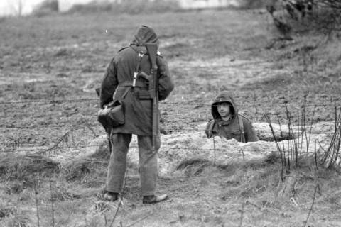 ARH NL Mellin 01-169/0005, Zwei Soldaten der Bundeswehr von einem Zaun getrennt auf und in einem Feld, ohne Datum