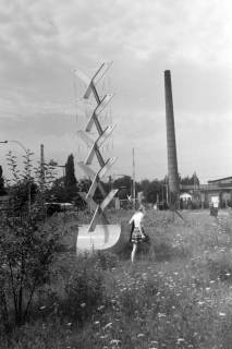 ARH NL Mellin 01-194/0005, Mädchen auf einer Wiese neben einer Statue(?), im Hintergrund ein Fabrikschornstein, ohne Datum