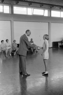 ARH NL Mellin 01-196/0015, Ehrung eines jungen Mädchens durch einen Herren in einer Sporthalle, ohne Datum