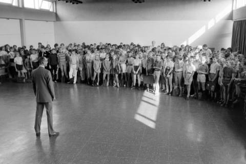 ARH NL Mellin 01-196/0017, Ein Mann (Lehrer?) steht vor versammelten Schüler*innen in einer Sporthalle, ohne Datum