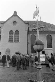 ARH NL Mellin 02-099/0015, Auf dem Boden stehende Kirchturmspitze mit Wetterhahn und versammelte Gruppe an Menschen auf dem Spitta-Platz an der Pankratiuskirche, Burgdorf, ohne Datum