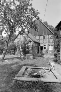 ARH NL Mellin 02-102/0006, Mädchen beim Spielen in einem Sandkasten im Vorgarten eines Fachwerkhauses, um 1970