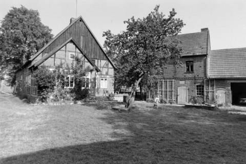 ARH NL Mellin 02-102/0008, Blick über den Vorgarten auf ein Fachwerkhaus und ein Nebengebäude, um 1970