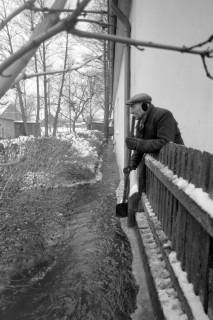 ARH NL Mellin 02-107/0014, Überschwemmtes Grundstück und Mann mit einer Schaufel am Grundstückszaun stehend, um 1970