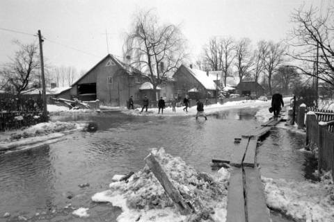 ARH NL Mellin 02-107/0015, Überschwemmte Straße mit Holzplanken zum Überqueren, um 1970