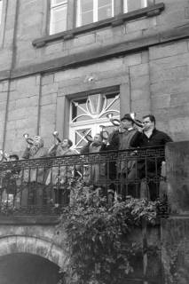 ARH NL Mellin 02-107/0018, Jagdhornbläser auf einem Balkon über einem Durchgang an einem Gebäude, um 1970