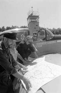 ARH NL Mellin 02-112/0006, Vier Männer des Feuerwehr-Flugdienstes Niedersachsen mit einer auf dem Flügel eines Flugzeuges ausgelegten Karte der Region Hannover , um 1975