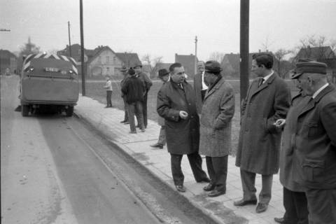 ARH NL Mellin 02-114/0012, Gruppe von Männern am Straßenrand stehend, links ein Fahrzeug zur Straßenreinigung, um 1975