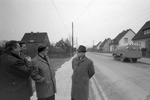 ARH NL Mellin 02-114/0014, Gruppe von Männern am Straßenrand stehend, rechts ein Fahrzeug zur Straßenreinigung, um 1975