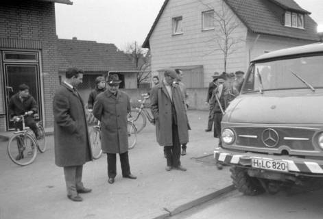 ARH NL Mellin 02-114/0015, Gruppe von Männern am Straßenrand stehend und ein Fahrzeug zur Straßenreinigung betrachtend, um 1975