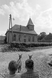 ARH NL Mellin 02-126/0004, Zwei Jungen in einem Wagen mit zwei vorgespannten Ziegen in einem Dorf, um 1975