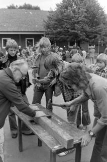 ARH NL Mellin 02-131/0015, Personen hämmern Nägel in einen Balken im Rahmen eines Festes, um 1975