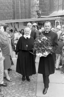 ARH NL Mellin 02-132/0005, Zwei Geistliche mit einer Blume im Topf laufen durch die Menschenmenge auf dem Altstadtmarkt an der St. Martini-Kirche, Braunschweig, um 1975