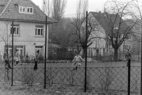 ARH NL Mellin 02-169/0004, Drei Männer bei einem Fußballspiel in einer Wohnsiedlung, um 1975