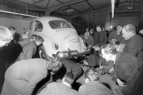 ARH NL Mellin 02-173/0013, Gruppe von Personen betrachtet ein aufgebocktes Auto in einer Autowerkstatt, um 1975