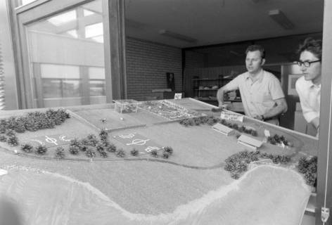 ARH NL Mellin 02-184/0009, Männer tragen eine Modellbauplatte mit Modell durch das Fenster eines Gebäudes, um 1970