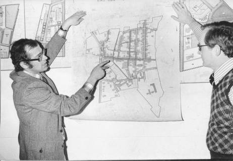 ARH Slg. Bartling 340, Städtischer Baudirektor Sigurd Trommer (li.) erläutert einen Stadtplan von Neustadt am Rübenberge., an der Wand gehalten von ihm und dem Angestellten Helmut Döring, 1974