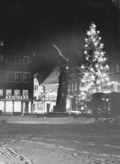 ARH Slg. Bartling 952, Kirchplatz am Abend im Schnee, Blick auf die Kastanie, die Apotheke und einen beleuchteten Tannenbaum, Neustadt a. Rbge., um 1975