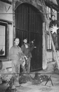 ARH Slg. Bartling 968, Junge Männer beim Anbringen einer vorweihnachtlichen Lichterkette am Giebel eines Fachwerkhauses in der Innenstadt, Neustadt a. Rbge., um 1970