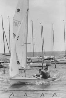 ARH Slg. Bartling 1092, Mit drei Mann besetztes Jeton-Boot in voller Fahrt vorm Wind vorbei an einem Anleger mit Booten, Steinhuder Meer, ohne Datum