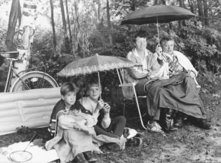 ARH Slg. Bartling 1155, Familie mit zwei Kindern am Waldrand (an der Weißen Düne?) unterm Regenschirm auf Luftmatratze bzw. Campingstühlen sitzend, Steinhuder Meer, um 1980