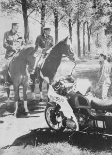 ARH Slg. Bartling 1161, Weißer Berg am Himmelfahrtstag (?), zwei berittene Polizisten unterhalten sich mit einem am Straßenrand neben seinem Motorrad (BMW R 65) stehenden Polizisten, Steinhuder Meer, Neustadt a. Rbge., um 1980