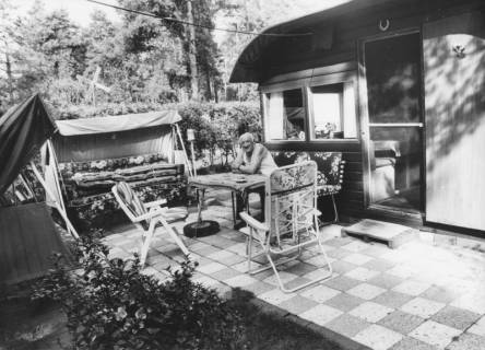 ARH Slg. Bartling 1166, Campingplatz am Bannsee, älterer Camper in Freizeitkleidung vor seinem Wochenendhaus auf einer Bank auf der Terrasse am Tisch sitzend, Steinhuder Meer, um 1980