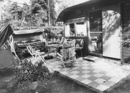 ARH Slg. Bartling 1167, Campingplatz am Bannsee, älterer Camper in Freizeitkleidung vor seinem Wochenendhaus auf einer Bank auf der Terrasse am Tisch sitzend, Steinhuder Meer, um 1980