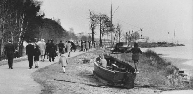 ARH Slg. Bartling 1210, Zahlreiche Spaziergänger in winterlicher Kleidung auf dem Uferweg, auf der leicht verschneiten Uferböschung ein Auswandererboot, Steinhuder Meer, 1971