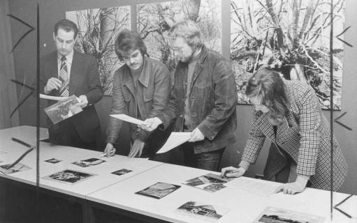 ARH Slg. Bartling 1355, Vier Mitglieder der Jury des 6. Foto-Wettbewerbs (3. von links: Peter Mumm) begutachten und bewerten die eingereichten, auf dem Tisch ausgelegten Fotos, Neustadt a. Rbge., 1974