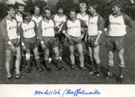 ARH Slg. Bartling 1392, Staffelmeister-Fußballmannschaft Mandelsloh, zehn Spieler im Trikot mit dem Werbeschriftzug "Colonia" auf dem Rasen locker nebeneinander stehend, Mandelsloh?, um 1980