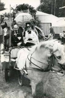 ARH Slg. Bartling 1507, Schützenfest, Aufbruch zu einer Kutschfahrt mit dem Pony vor dem Festzelt, in Phantasiekostüm auf dem Wagen sitzend: Herr Kabirschke und Frau Haas, Bevensen, 1974