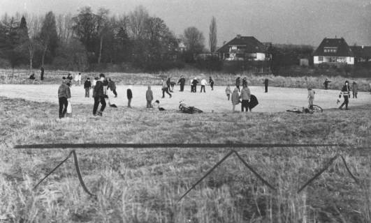 ARH Slg. Bartling 1521, Winterliches Eisvergnügen von Jugendlichen auf dem vereisten Teich in der Leineaue östlich der Schlossbastion, im Hintergrund einzelne Häuser der Apfelallee, Neustadt a. Rbge., 1973
