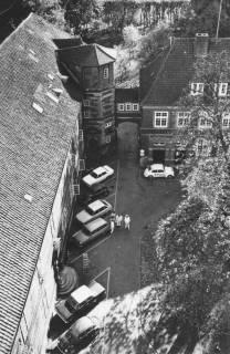 ARH Slg. Bartling 1572, Schlosshof, Blick vom Kran oberhalb des nördlichen Treppenturms nach Süden auf das Dach des Ostflügels, den Schlosshof mit parkenden Autos, das südliche Gebäude und den Amtsgarten, Neustadt a. Rbge., 1972