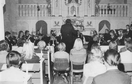 ARH Slg. Bartling 1761, Konzert eines Sinfonieorchesters im Altarraum der Kirche zu Niedernstöcken, Blick über die Hinterköpfe der Zuhörer auf das Orchester und den Altar, Niedernstöcken, 1974