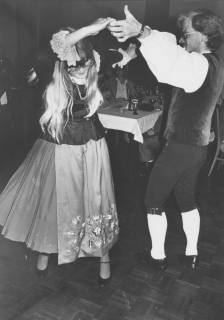 ARH Slg. Bartling 1767, Junges Paar, in Tracht gekleidet (die Frau links mit Jacke und 3/4 langem Rock sowie bestickter Schürze, der Mann mit ärmelloser Trachtenweste, Hemd mit Trompetenärmeln und Kniebundhose sowie weißen Strümpfen), tanzt einen Volkstanz, Neustadt a. Rbge., um 1975