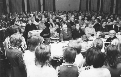 ARH Slg. Bartling 1877, Gruppe von musizierenden Kindern bei einer Veranstaltung des Seniorenclubs NRÜ, Blick von der Bühne über die Hinterköpfe der Kinder in den Saal mit den an langen Tafeln sitzenden Senioren, Neustadt a. Rbge., 1972