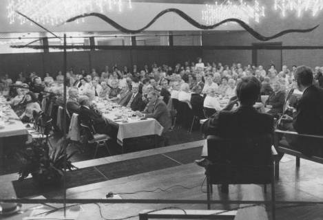 ARH Slg. Bartling 1886, Senioren und Seniorinnen an langen Tischen einer Kaffeetafel bei einer Podiumsdiskussion im Freizeitzentrum, Blick über zwei Teilnehmer des Podiums in den Saal, Neustadt a. Rbge., 1972