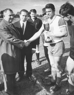 ARH Slg. Bartling 1970, Überreichung eines Pokals an den Spielführer des FC Wacker N. N. durch Adolf Wassmann sen. und jun., im Hintergrund beobachtend ein Schiedsrichter, 1970