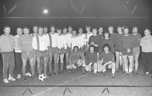 ARH Slg. Bartling 1989, Zwei Fußballmannschaften vor dem Anstoß am Mittelkreis nebeneinander aufgereiht und stehend, am Abend im Flutlicht, Blick von vorn, 1975