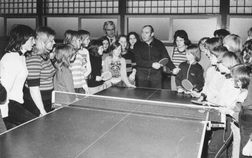 ARH Slg. Bartling 2078, Tischtennis-Lehrstunde für Kinder und Jugendliche, die sich rund um eine Tischtennisplatte aufgestellt haben, in einer Sporthalle (in der Mitte der Trainer), Bordenau, 1974