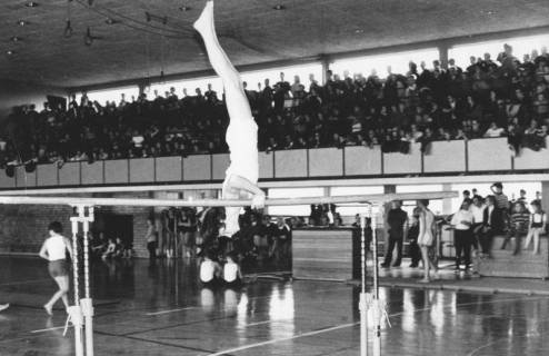 ARH Slg. Bartling 2119, Turner in gestrecktem Oberarmstand am Barren, Blick in die TSV Turnhalle auf die vollbesetzte Zuschauertribüne, Neustadt a. Rbge., 1974