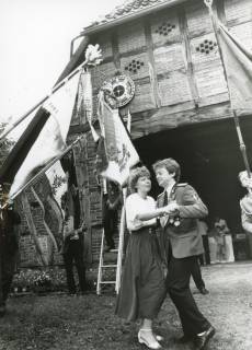ARH Slg. Bartling 2157, Annageln der Königsscheibe über dem Tor einer Fachwerksgiebelwand, davor das Königspaar beim Tanz unter den Fahnen beim Schützenfest, Basse, um 1985