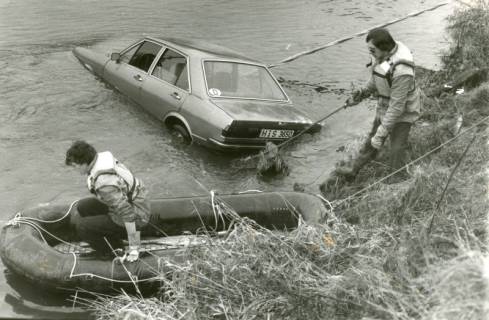 ARH Slg. Bartling 2162, Bergung eines PKWs (AUDI 80) aus der Leine durch zwei Feuerwehrleute (einer am Ufer, ein anderer im Schlauchboot am Ufer), Basse, um 1975