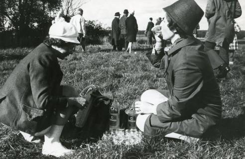 ARH Slg. Bartling 2177, Zwei Damen (einer Jagdgesellschaft) auf einer Wiese knieend beim Portionieren und Probieren von Hardenberger Korn, 1970
