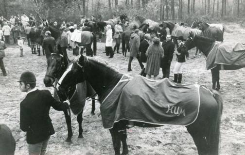 ARH Slg. Bartling 2192, Reitgesellschaft samt Pferden, die mit Decken geschützt sind, beim "Bügeltrunk" des Reit- und Fahrvereins in der Sandkuhle, Rodewald, 1971